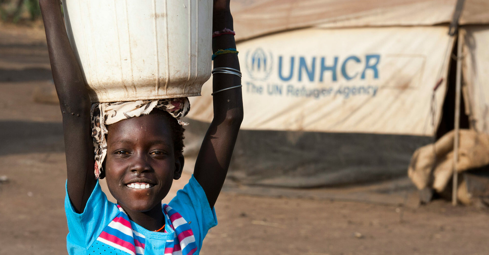 Kind mit Eimer auf dem Kopf und UNHCR Logo RF198400_1920x1080.jpg