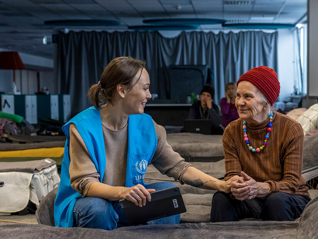 UNHCR-Helferin mit älterer Flüchtlingsfrau