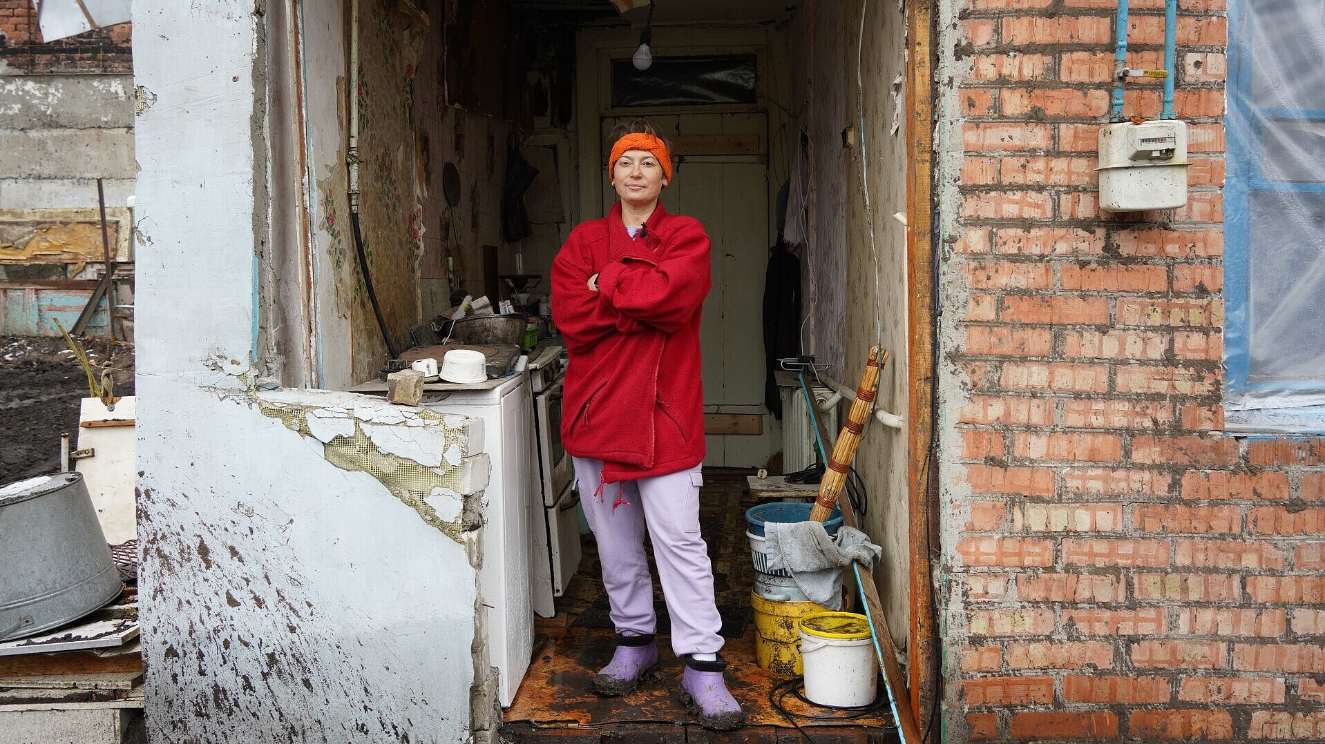 Frau steht in der Tür zu ihrem zerbombten Haus