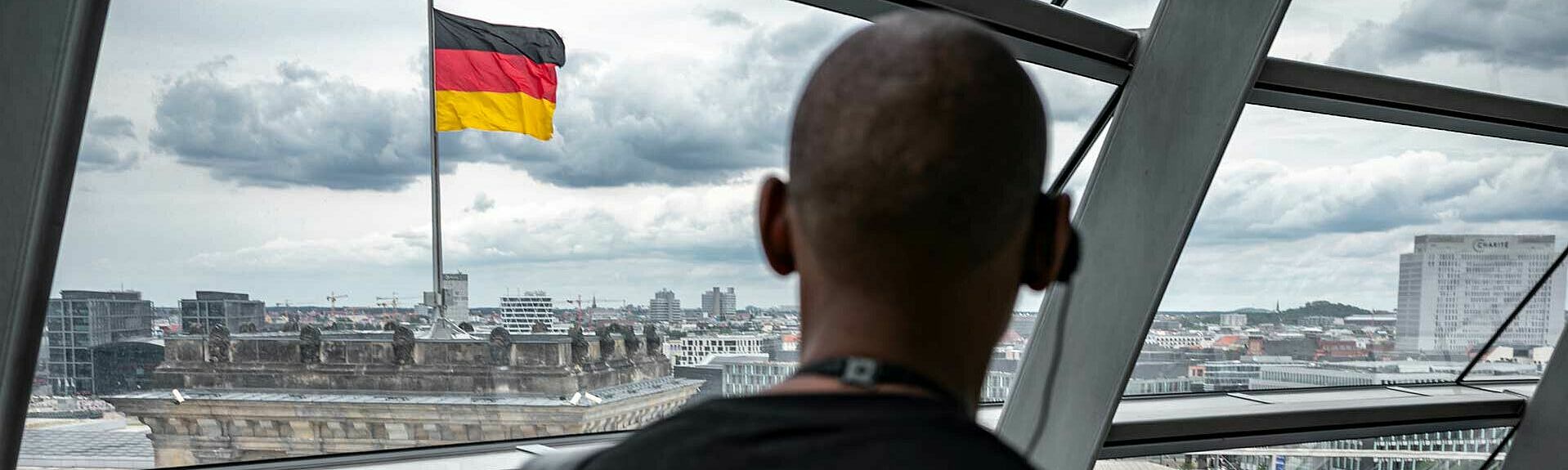 Person von hinten mit Bundestag und Deutschlandflagge im Hintergrund