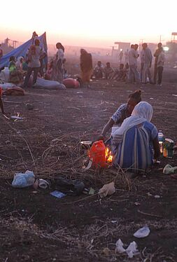 Flüchtlinge sitzen in Gruppen in Abenddämmerung