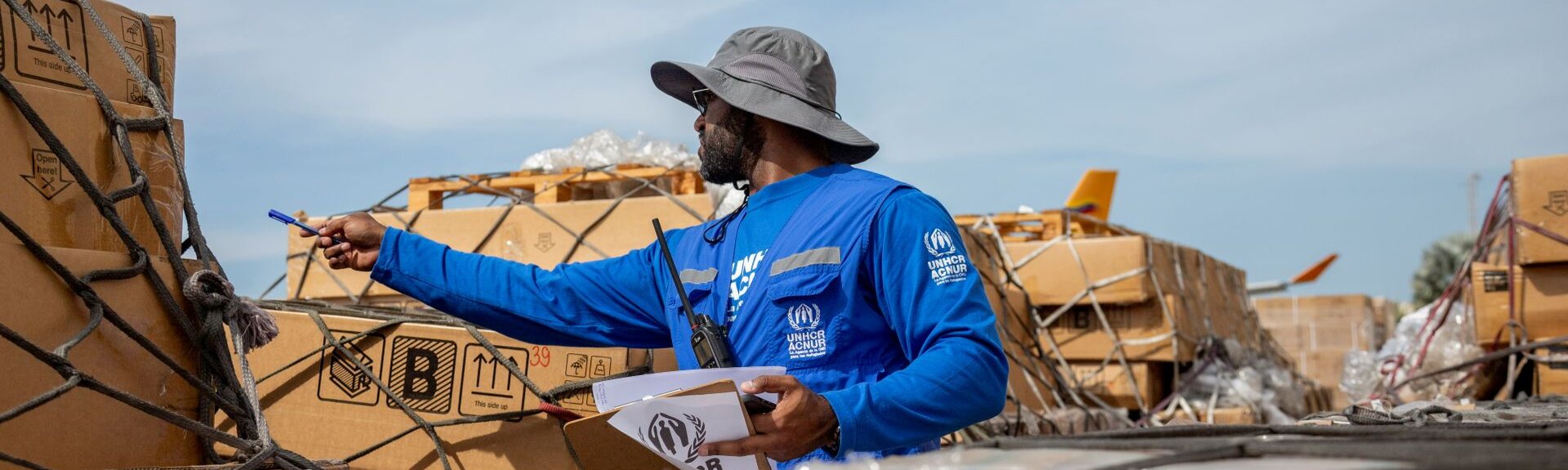 Ein Mann in UNHCR Jacke deligiert Hilfsgüter