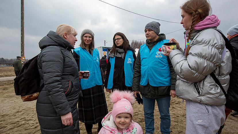 UNHCR-Mitarbeiter geben Flüchtlingen aus der Ukraine am Grenzübergang Madyka nach Polen erste Informationen.