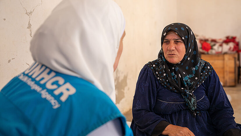 Eine ältere frau im Gespräch mit einer anderen Frau in UNHCR Weste