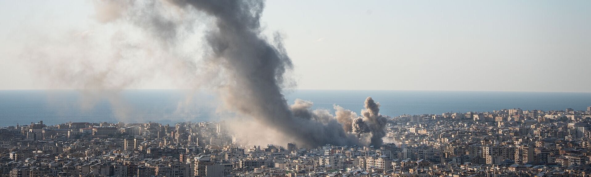 Blick über Stadt mit Rauchwolke von Bombeneinschlag