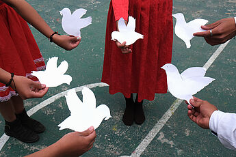 Mädchen halten weiße Papiertauben in den Händen