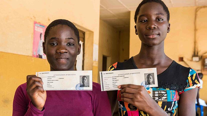 Ausweisdokumente: Zwei geflüchteten Schwestern, die nun ivorische Staatsbürgerinnen sind, halten ihre Ausweispapiere in der Hand.
