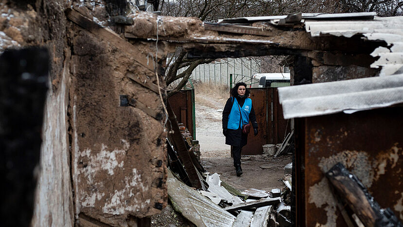 Eine UNHCR-Mitarbeiterin besucht die Bewohner eines stark beschädigten Hauses in Avdiivka, Donezk.