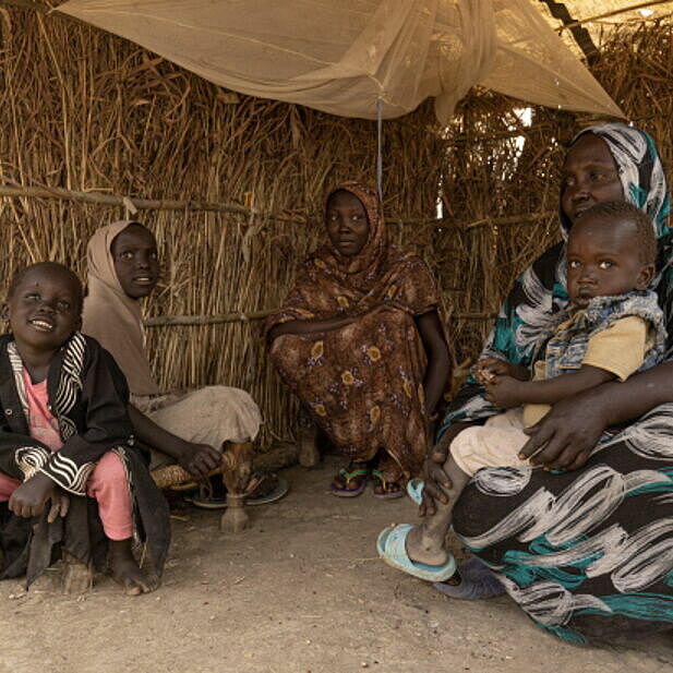 Eine sudanesische Familie sitzt in einer Unterkunft