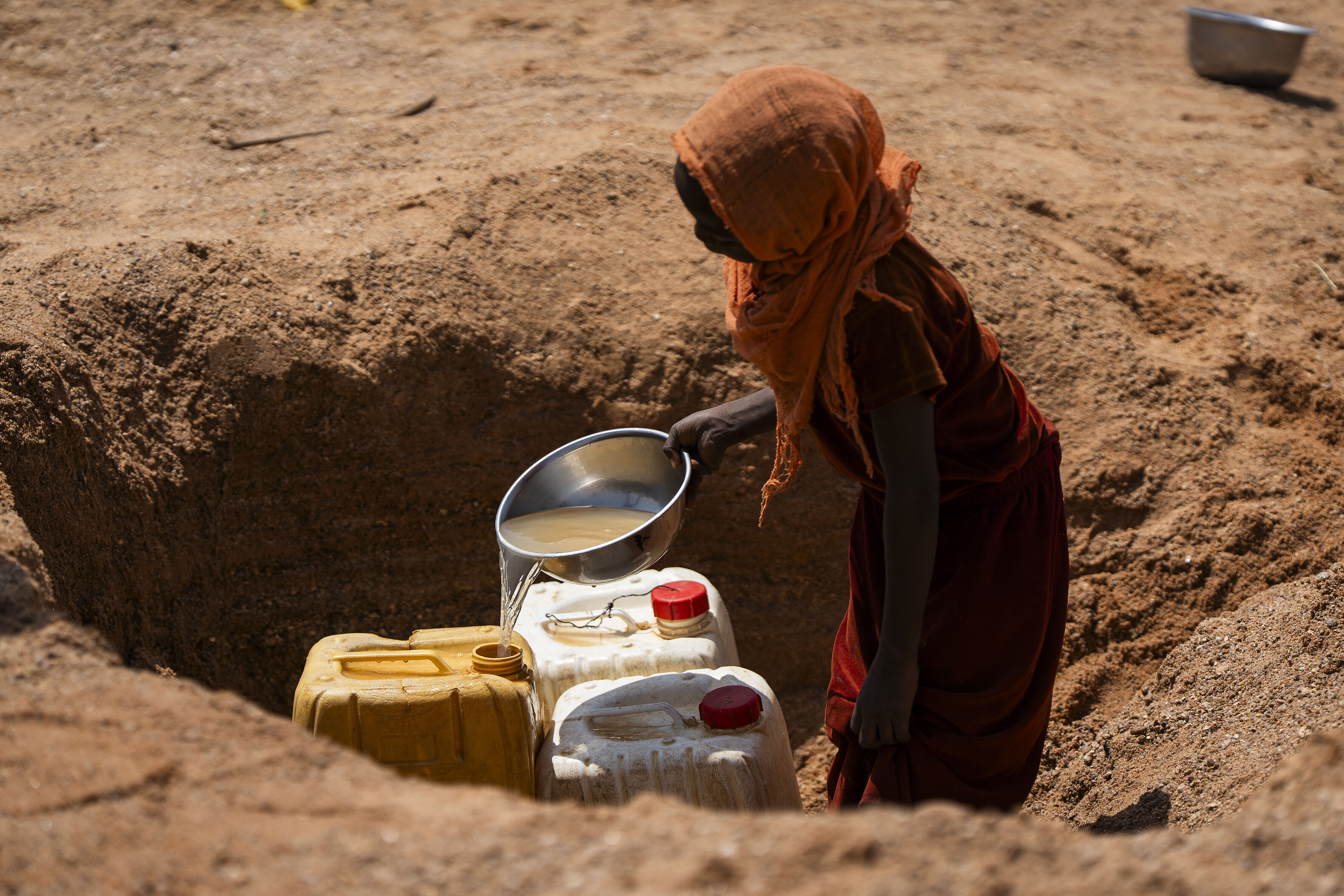 Eine Frau gießt bräunliches Wasser in einige Karnister