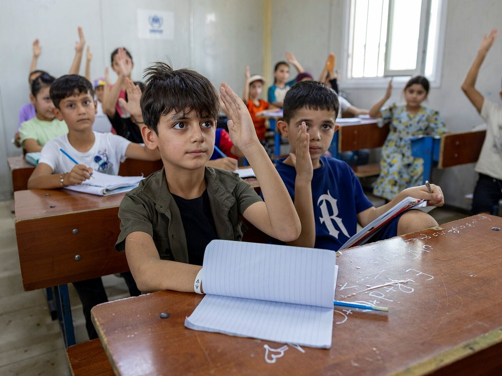 Schulkinder an tischen mit Papier, sie melden sich