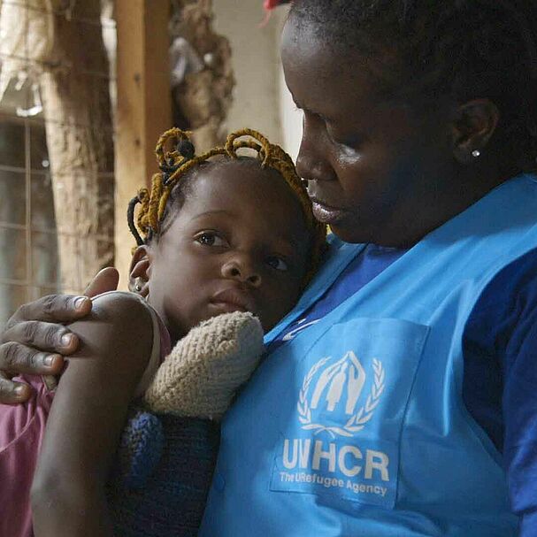 UNHCR-Helferin mit Kind auf dem Arm