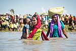 Rohingya Fraune in Fluss mit Kind auf dem Arm, Hindergrund Gruppe