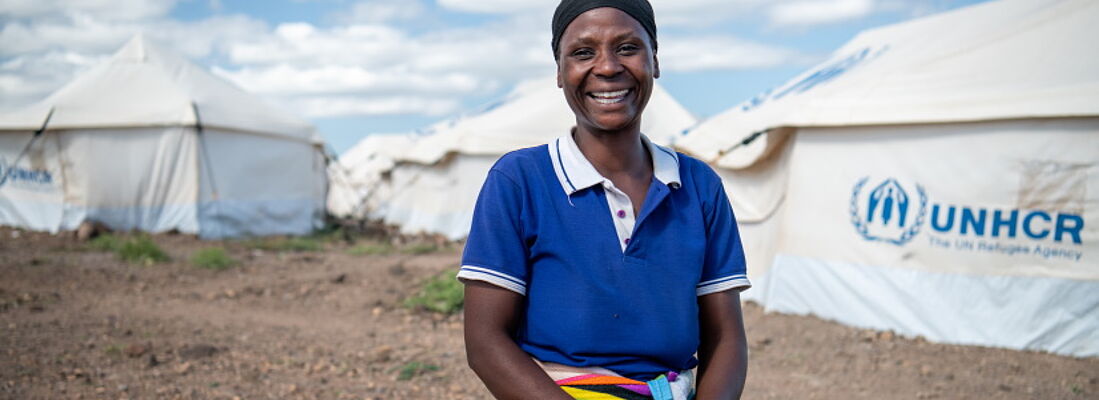 Lächelnde Frau vor UNHCR Zelten