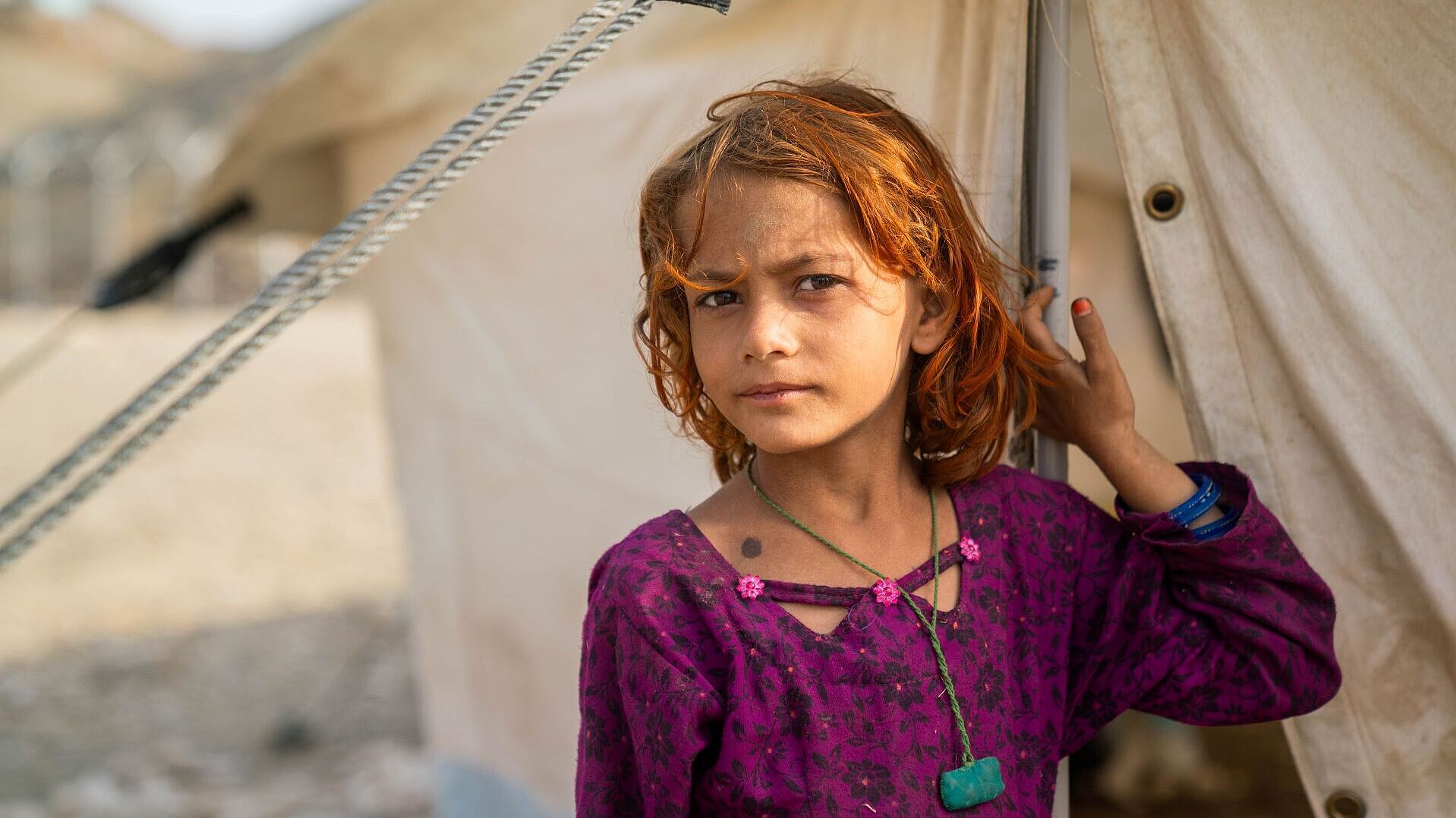 Kleines Mädchen steht vor einem Zelteingang