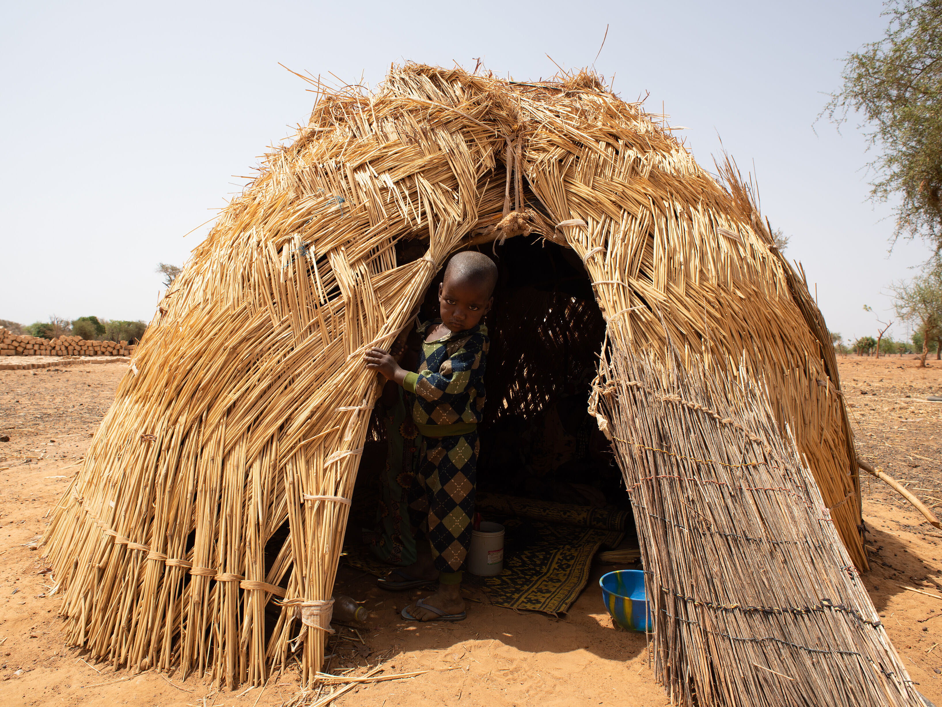 Ein Kind schaut aus einer Strohhütte raus