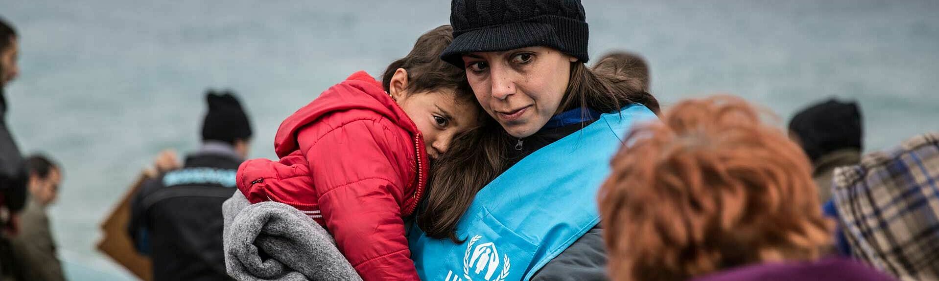 UNHCR-Helferin mit Kind auf dem Arm