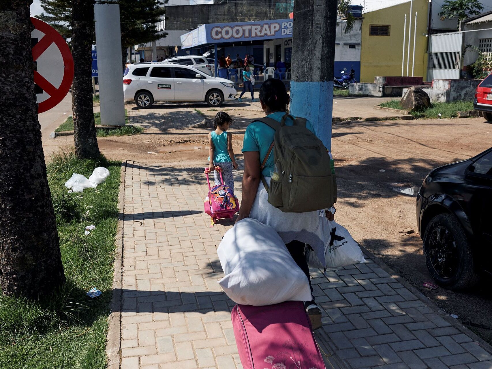 Eine Mutter und ihr Kinde ziehen ihr Gepäck über en Gehweg