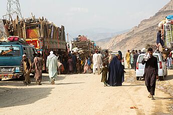Straßenszene am Grenzübergang in Afghanistan mit Menschen und LKW