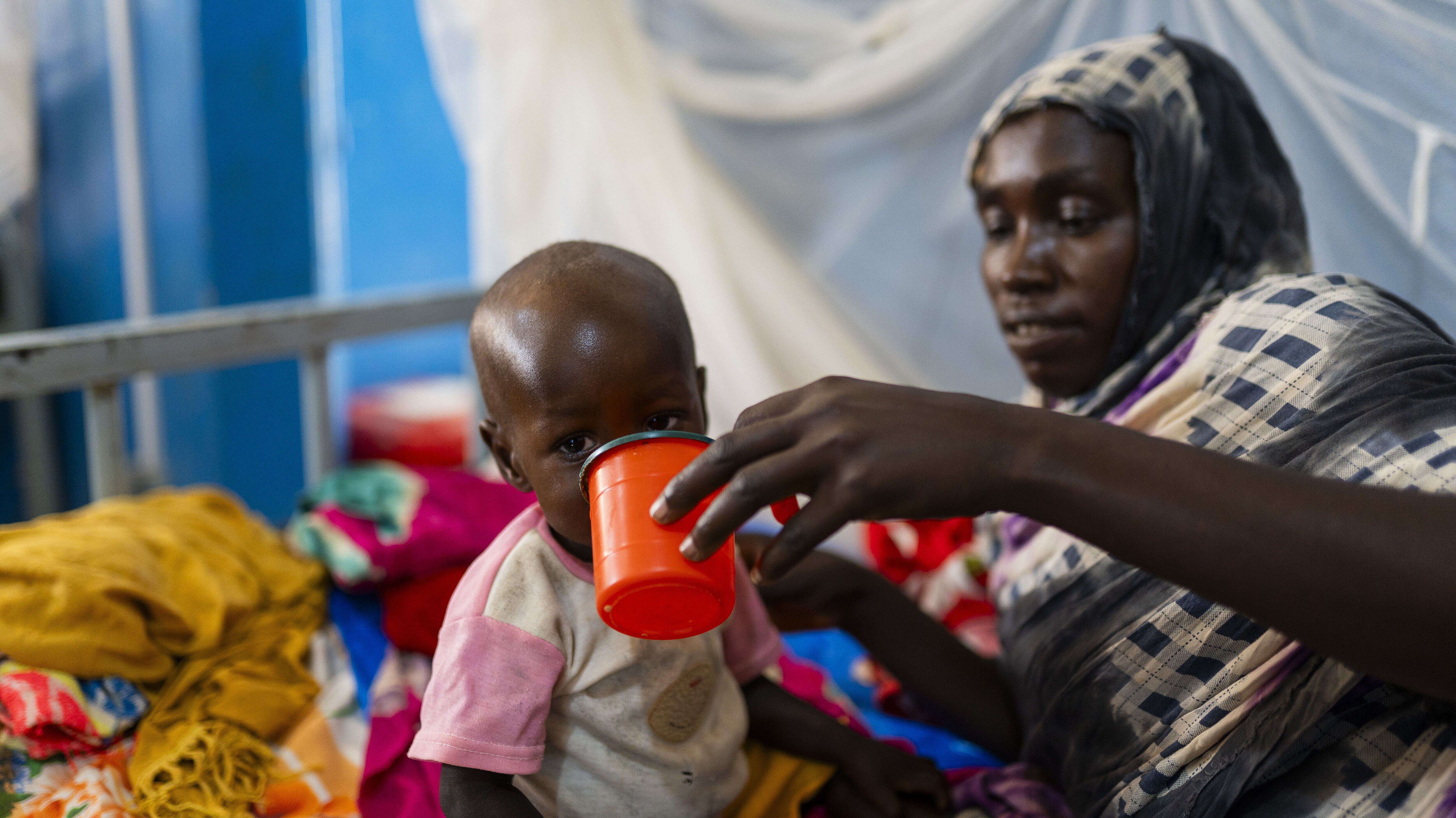 Mutter die ihr Kind mit einem Becher füttert