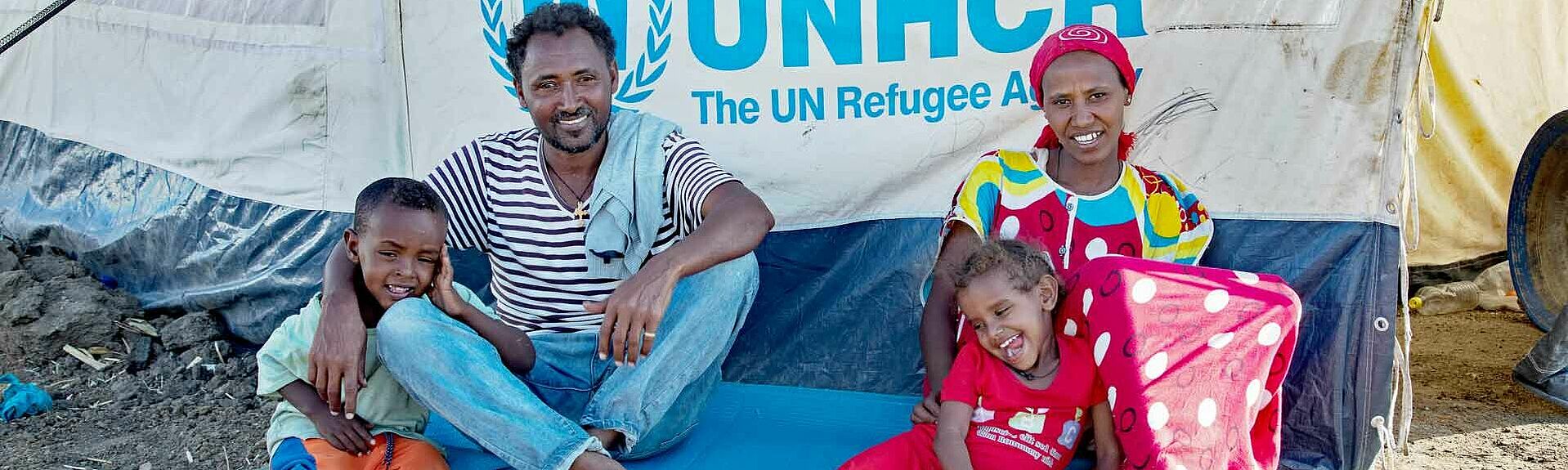 Flüchtlingsfamilie sitzt vor Zelt
