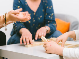 Drei paar Hände um ein Spiel mit Holzklötzen herum