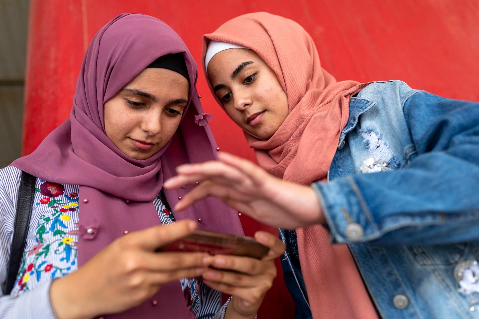 Zwei Flüchtlingsmädchen mit Handy in der Hand
