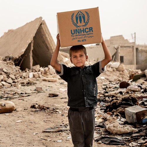 Junge mit UNHCR-Hilfspaket über dem Kopf