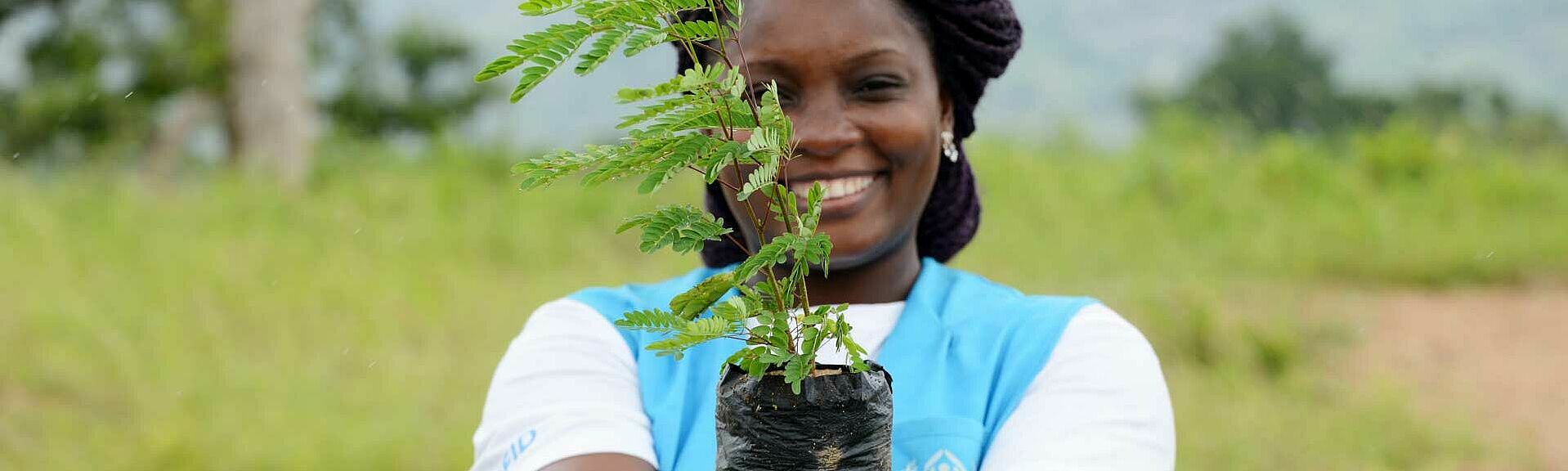 UNHCR-Mitarbeiterin mit Pflanze in der Hand