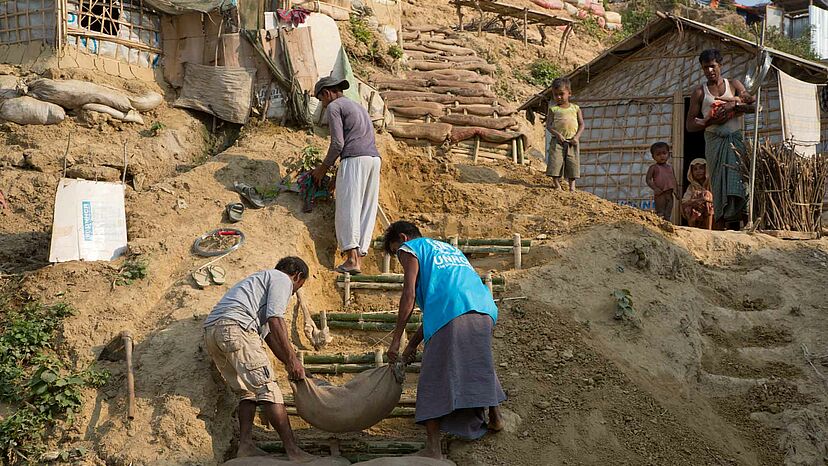 Vorbereitung auf die Monsunzeit
Das Flüchtlingslager Kutupalong in Bangladesch beherbergt fast 600.000 Rohingya-Flüchtlinge auf engstem Raum und ist damit zur Zeit das größte Flüchtingslager weltweit. In der Monsunzeit gefährden Erdrutsche, Überschwemmungen und Stürme die Bewohner. Durch Terassenbauten und Abwassermanagement wird versucht, die größten Schäden zu vermeiden, doch immer wieder werden hunderte Unterkünfte beschädigt oder zerstört.