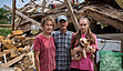 Oksana, Jurij und Tochter Svitlana vor ihrem zerstörten Haus in Nalyvaikivka, in der Oblast Kiew. Die Familie hatte sich in ihrem unterirdischen Kühlraum versteckt, als das Haus während der russischen Invasion von zwei Raketen getroffen wurde. Derzeit lebt die Familie in einer UNHCR-Unterkunft, die ihr nach dem Angriff zur Verfügung gestellt wurde.
