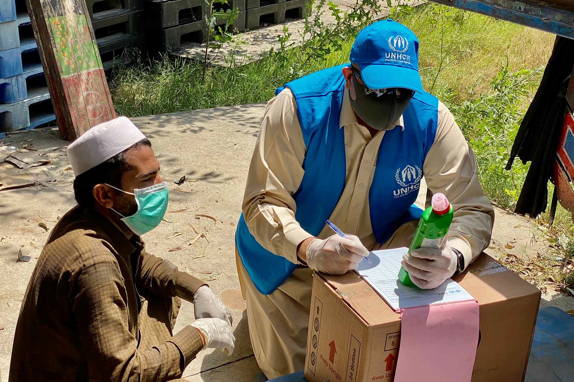 UNHCR-Mitarbeiter teilt Desinfektionsmittel aus