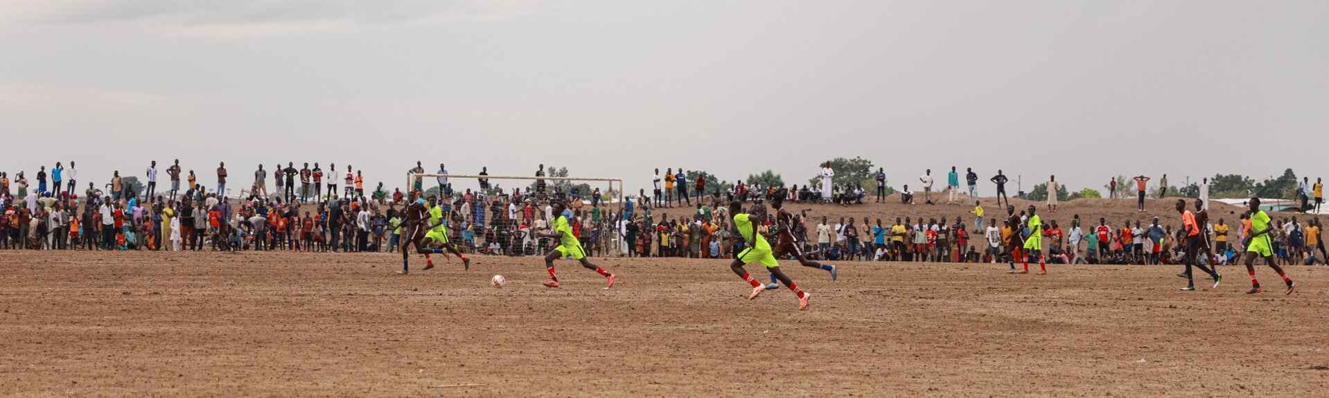 Fußballspiel auf staubigem Spielfeld in Afrika
