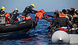 Mitarbeitende von SOS Humanity überreichen Schwimmwesten an die Besatzung eines Schlauboots