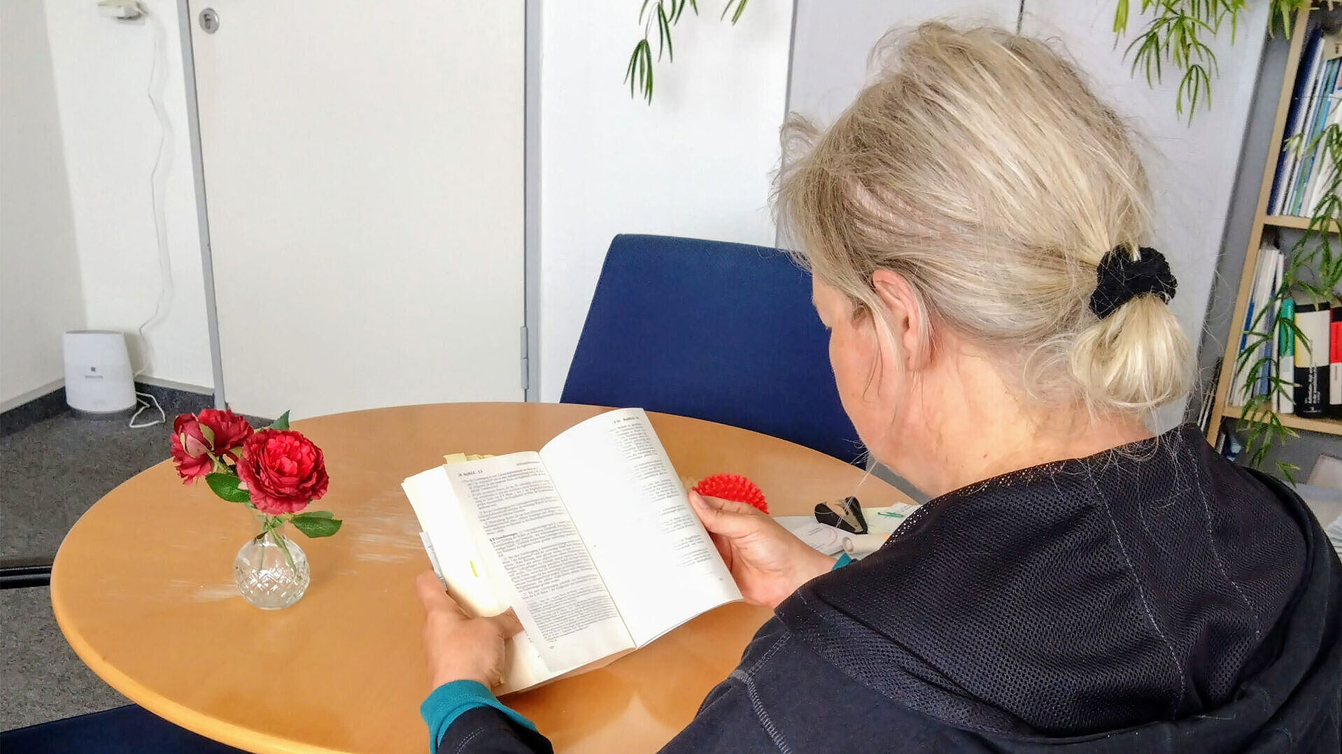 Frau von hinten lesend am Tisch sitzend