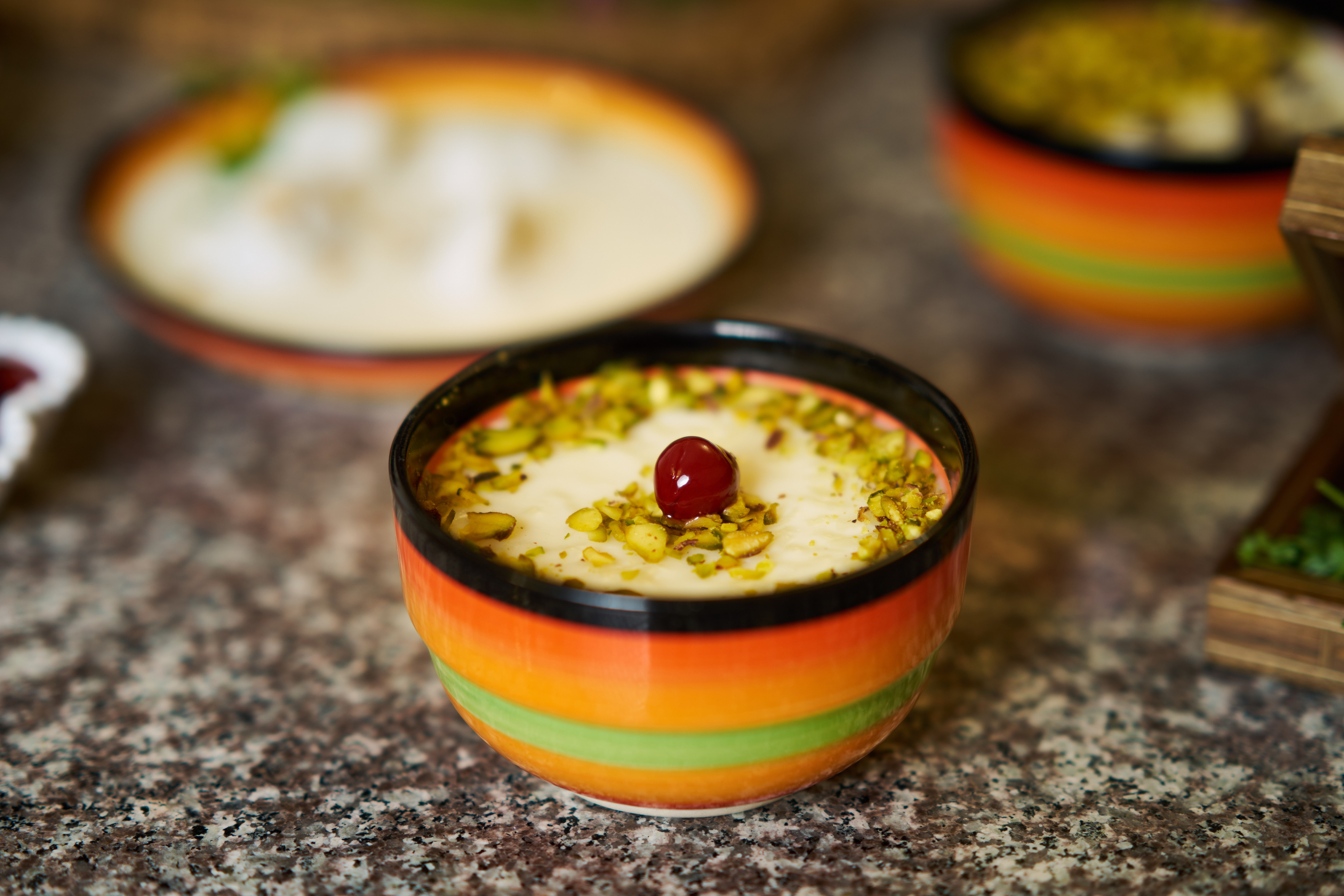 Eine Schale mit Nüssen und einer Kirsche garniertem Reispudding