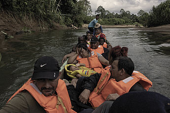 Geflüchtete sitzen nach der Durchquerung des DariénDschungels völlig erschöpft in einem Kanu auf dem Membrillo Fluss nach Puerto Limon