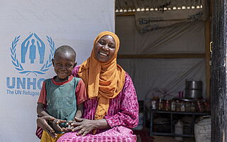 Mutter und Sohn vor UNHCR-Zelt