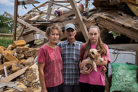 Ukrainische Familie vor zerstörtem Haus