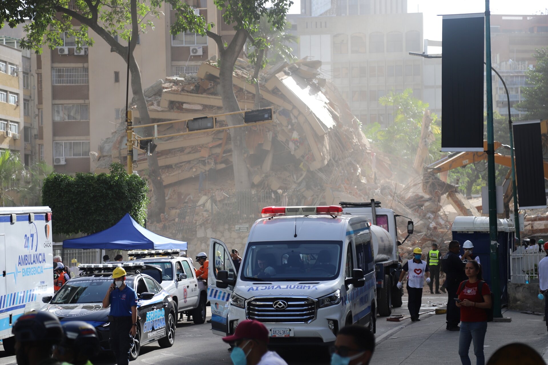 Straßenzug in Caracas, mit Rettungswagen und eingestürztem Hochhaus.