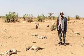 Ein Binnenvertriebener aus Äthiopien steht inmitten einer verdorrten Landschaft, Tierkadaver liegen auf dem Boden