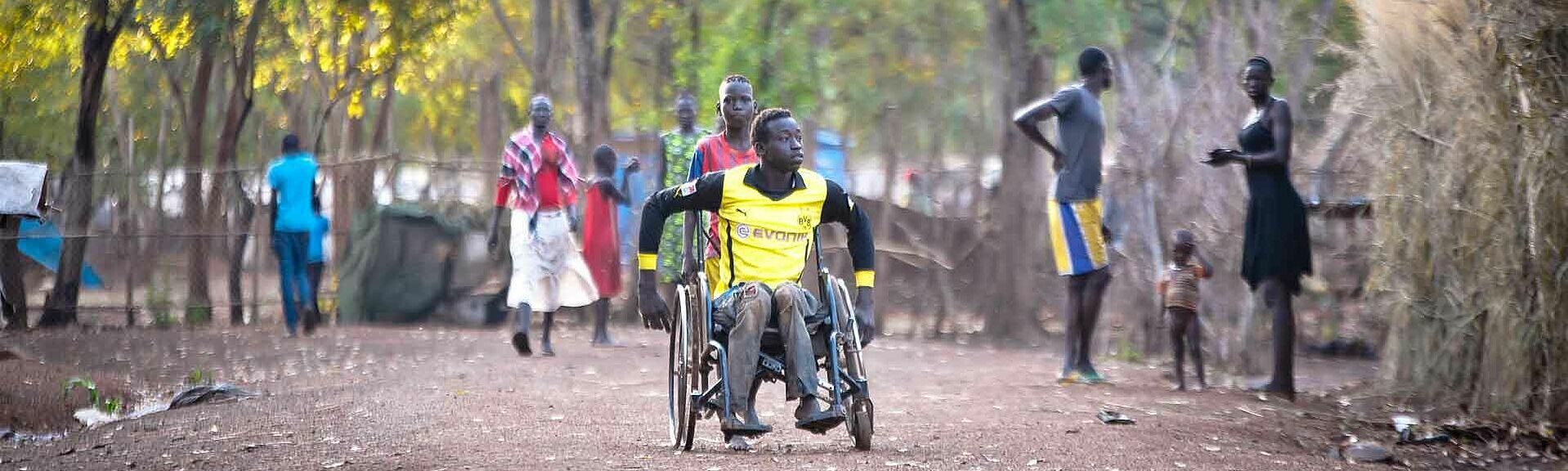 Junger Mann im Rollstuhl in afrikanischem Flüchtlingslager