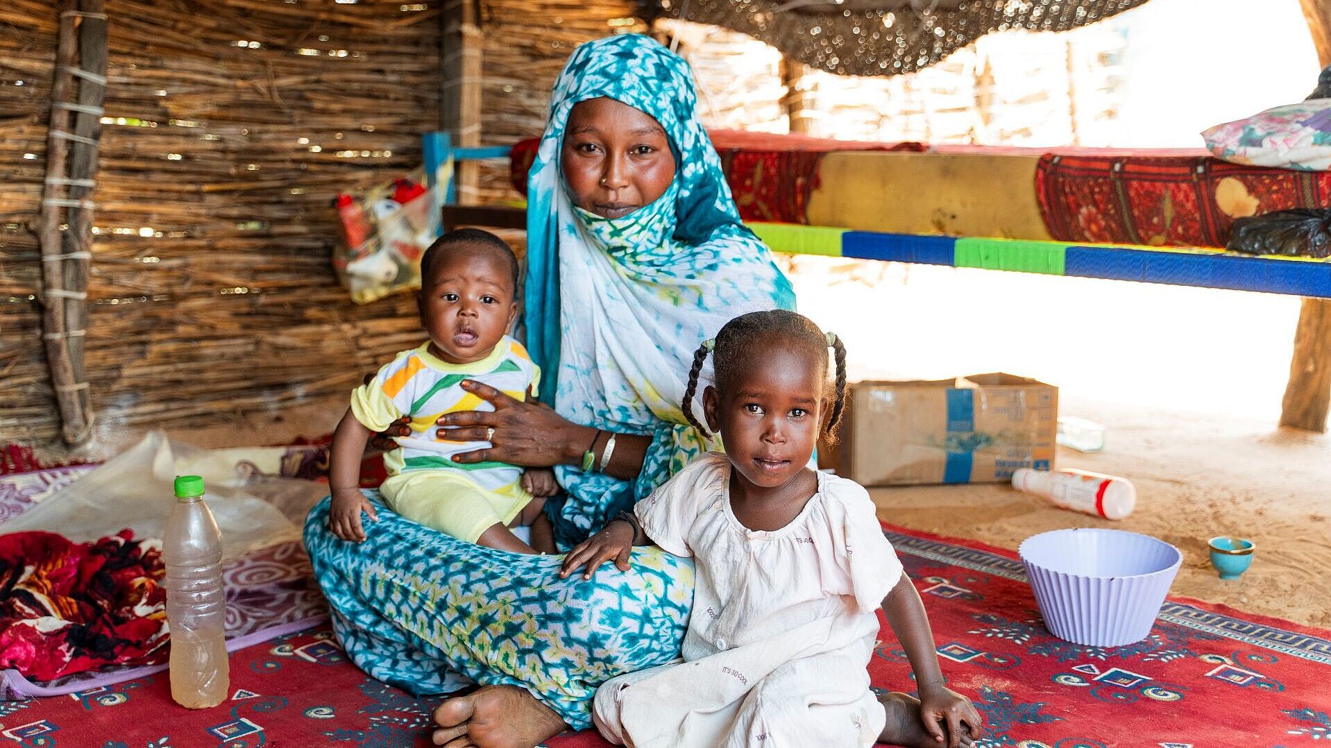 Eine Mutter mit Baby und kleinkind sitzen auf dem Boden