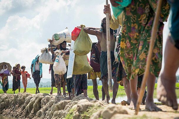 Schlange an Rohingya Flcühtlingen mit Gepäck, Krieg und Gewalt