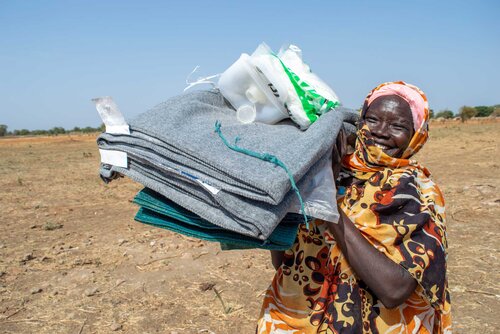 Frau mit Hilfsgütern auf dem Arm