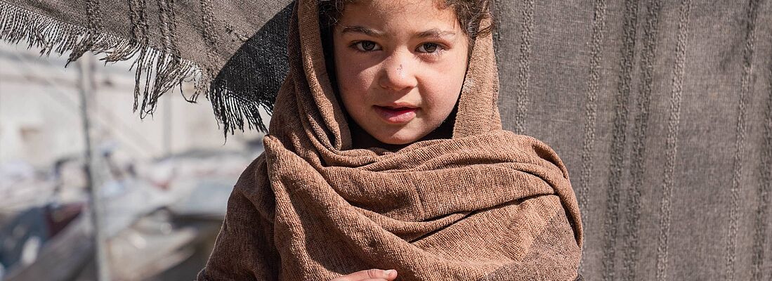 Die 6-jährige Nilofar lebt mit ihrer Familie in einem Zelt in einer informellen Siedlung, wo sie mit den Herausforderungen der Vertreibung und den harten Lebensbedingungen konfrontiert ist. 