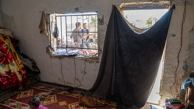 Eine Tür, dei nur von einem Tuch dürftig abgedeckt ist und ein kaputtes Fenster in einem allgemein kaputten Haus
