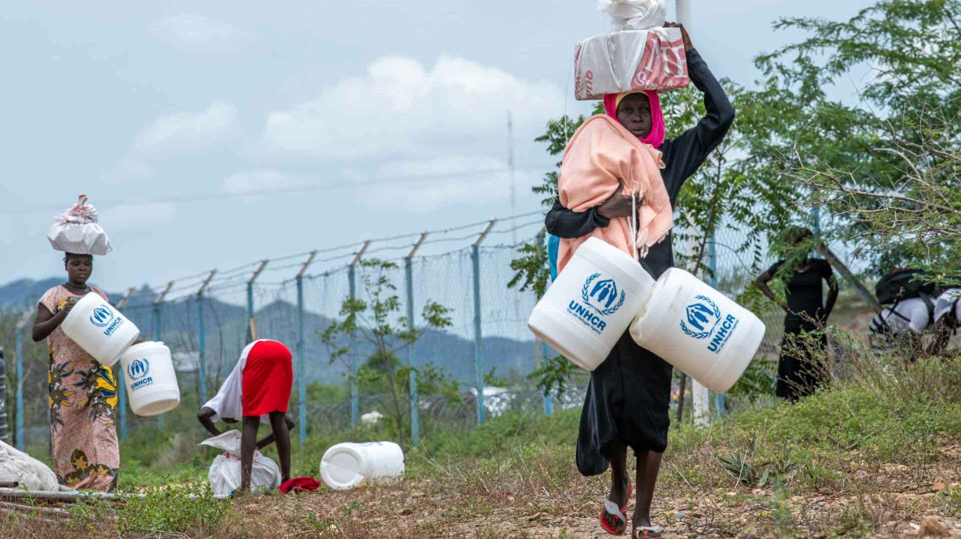 Flüchtlinge tragen Wasserkanister