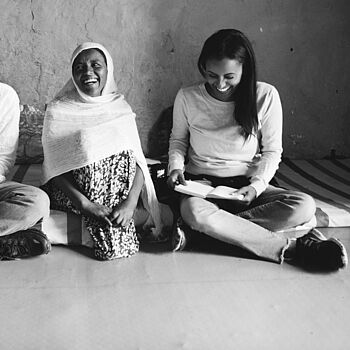 Drei frauen lachend, auf dem Boden sitzend in schwarz weiß