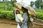 Mädchen mit kleinen Kind auf dem Arm unter Regenschirm, Staatenlose